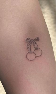 a small cherry tattoo on the left thigh, with two cherries attached to it