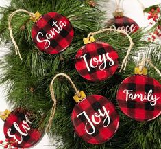 christmas ornaments with the word joy on them hanging from a pine tree in front of white background