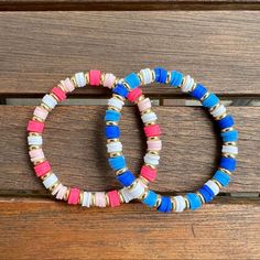 two bracelets sitting on top of a wooden bench next to each other with different colored beads