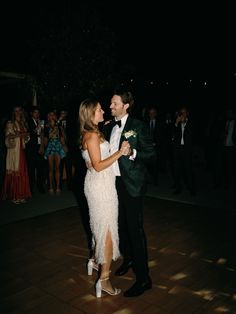 a bride and groom dance together on the dance floor at their wedding reception in front of an audience