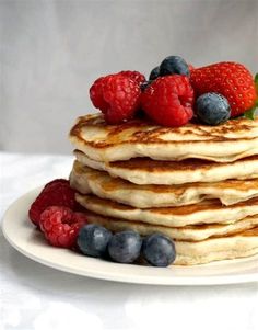 a stack of pancakes topped with berries and blueberries