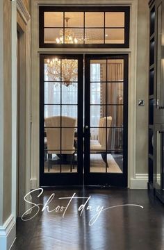 an entry way with black doors and chandelier