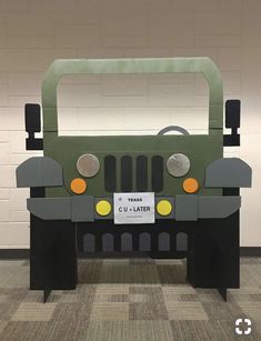 a green truck made out of cardboard sitting on top of a checkered carpeted floor