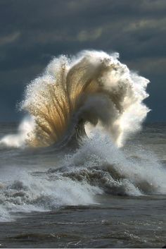 a large wave crashing into the ocean on a stormy day