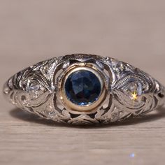 The Sound View Road: Antique Filigree Ring Set With Sapphire And Diamonds. The Ring Centers On A Bezel Set Modified Round Brilliant Cut Natural Sapphire In A White Gold Bezel. The Sapphire Has An Approximate Weight By Measurement Of 0.30 Carats And Is Likely Of Montana Origin. Surrounding The Center Is An Intricate Filigree Pattern In Platinum Set With Old-Cut Round Diamonds. The Ring Is Crafted In Platinum And 18 Karat White Gold And Is Circa 1911 Per The Partial Original Engraving. The Ring Is Currently A Finger Size 5.5 Yet Can Be Adjusted To Any Finger Size For An Additional Charge On Request. Antique Filigree, Filigree Pattern, Filigree Ring, Natural Sapphire, The Sound, Bezel Setting, Womens Jewelry Rings, Round Brilliant, Ring Set