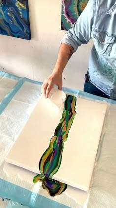 a man is painting on a piece of white paper with multicolored lines in it