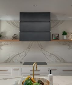 there is a bowl of fruit on the kitchen counter top next to an oven hood