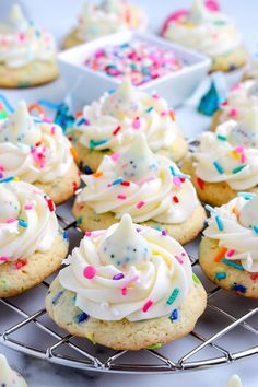 cupcakes with white frosting and sprinkles on a cooling rack