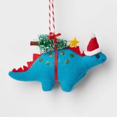 a blue dinosaur ornament with a christmas tree on it's back hanging from a red ribbon