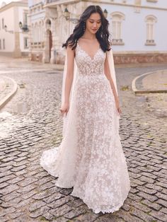 a woman in a wedding dress standing on a cobblestone street