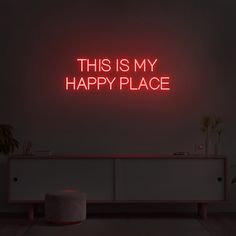 this is my happy place neon sign on the wall above a dresser in a dark room