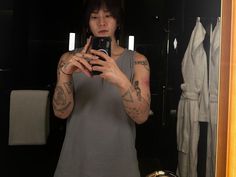 a woman taking a selfie in front of a mirror with tattoos on her arms