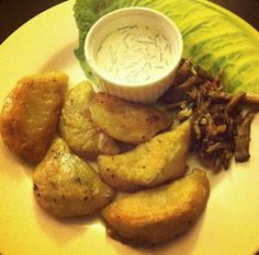 a white plate topped with fried potatoes and lettuce next to a dipping sauce