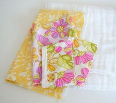 three folded napkins on top of each other in different colors and patterns, one with a flower design