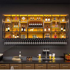 a bar with lots of bottles and glasses on the shelves above it is illuminated by yellow lights