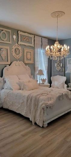 a white bed sitting in a bedroom next to a chandelier on a wall