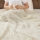 a woman sitting on top of a bed next to a white blanket