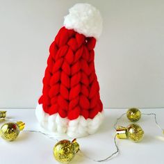 a red and white knitted santa hat next to gold ornaments