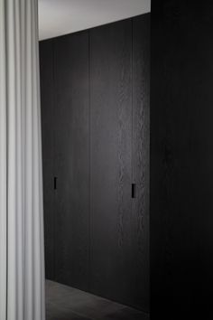 an empty room with black cabinets and white curtains