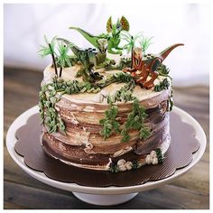 a cake decorated with green plants and dinosaurs