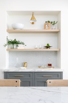 a kitchen with gray cabinets and white counter tops, gold accents on the top shelf