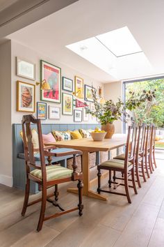 a dining room table and chairs with pictures on the wall above it, along with potted plants