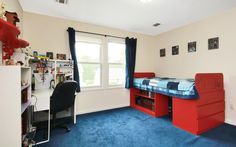 a bedroom with blue carpet and red furniture