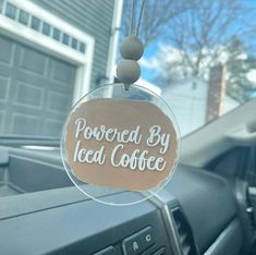 a sign that says powered by iced coffee hanging from the dashboard of a car