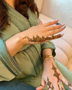 a woman sitting on a couch with her hands covered in hendix and tattoos