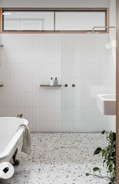 a white bath tub sitting under a window next to a sink