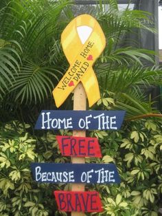 a wooden sign that says home of the free because of the brave with a yellow ribbon on it