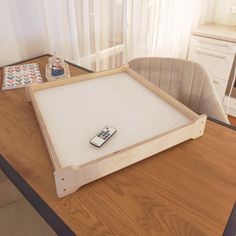 a remote control sitting on top of a wooden table in front of a white curtain