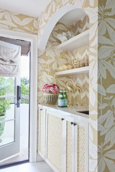 a kitchen with white cabinets and floral wallpaper on the walls, along with open shelves