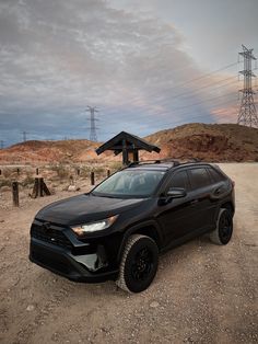 a black toyota rav is parked in the dirt