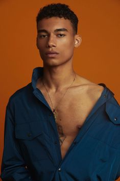 a young man with no shirt on posing for a photo in front of an orange background