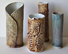 four different vases are lined up on the table, one is decorated with intricate designs