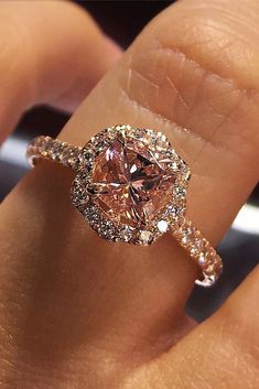 a woman's hand with a pink diamond ring on top of her finger,