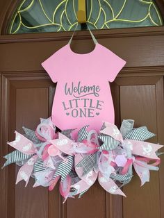 a welcome little one door hanger with pink and white ribbons on it's front door