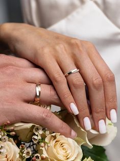 the bride and groom are holding each other's hands with wedding rings on their fingers