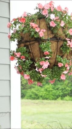 a hanging planter filled with pink flowers on the side of a house window sill