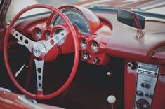 the interior of an old car with red leather steering wheel and gauges on it