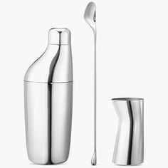 a stainless steel cocktail shaker next to a silver spoon