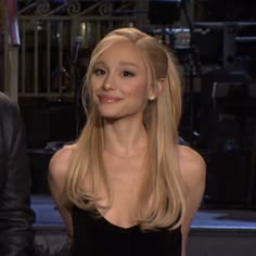 a woman with long blonde hair is sitting next to a man in a black suit