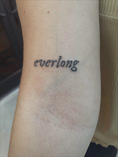 a woman's arm with the word everlong tattooed on her left side leg