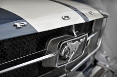 the front end of a mustang car with chrome and black stripes on it's hood