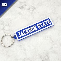 a blue and white keychain with the name jackson state on it sitting on a marble surface