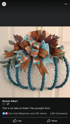 a white pumpkin with blue and orange bows on it's head is hanging from the front door