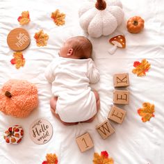 a baby laying on top of a bed surrounded by fall decorations