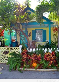 a small yellow house surrounded by tropical plants