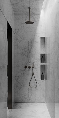 a bathroom with marble walls and flooring, shower head in the corner next to shelves